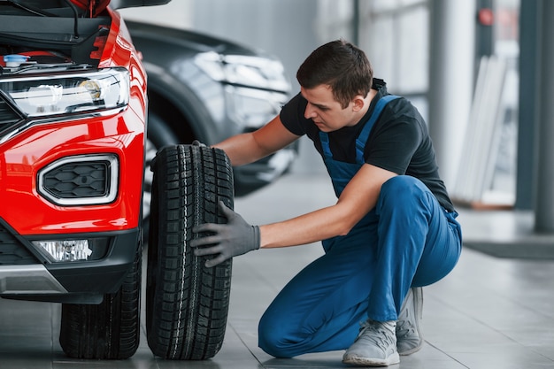 Man in uniform veranderende band van auto. Conceptie van autoservice