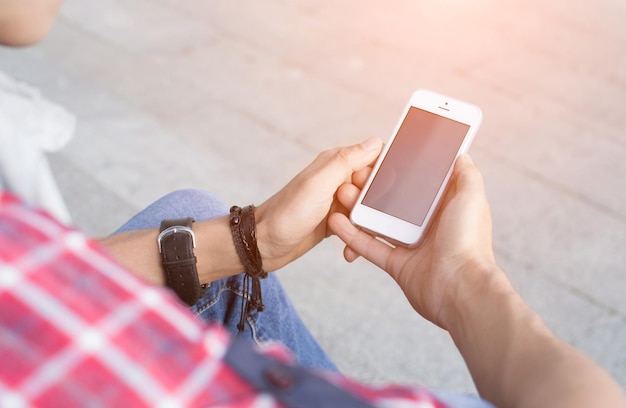 Man in vrijetijdskleding voelt zich op zijn gemak als hij op de trap zit en een telefoon vasthoudt