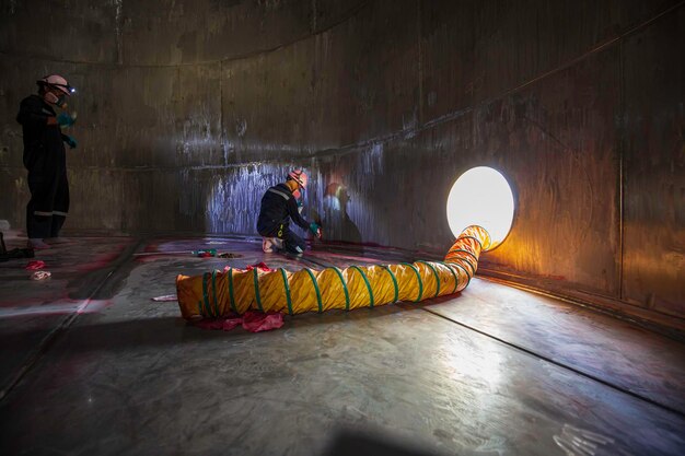 Man in werkinspectieproces chemische kleur verf kapblazer verse lucht in besloten ruimte van olieopslagtank