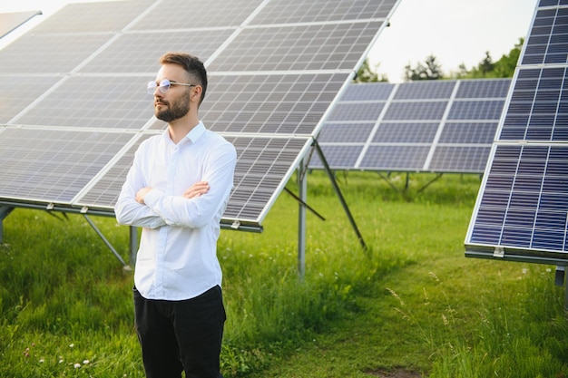 Man in wit overhemd staande in de buurt van fotovoltaïsche panelen op een zonnige dag op het platteland