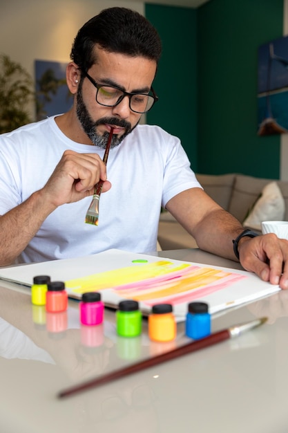 man in wit t-shirt die kunsttherapie beoefent, schilderdoek met gekleurde verf met een penseel