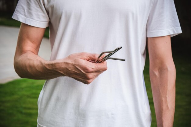 Man in witte t-shirt met een herbruikbaar stalen rietje Eco-levensstijl en zero waste-concept Plasticvrij