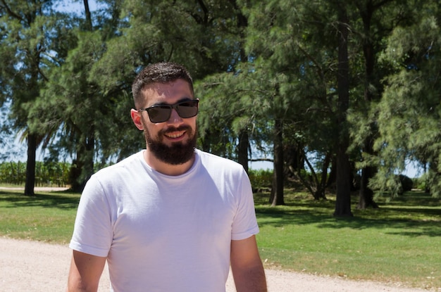 Man in witte tshirt baard en zonnebril op boerderij glimlachend