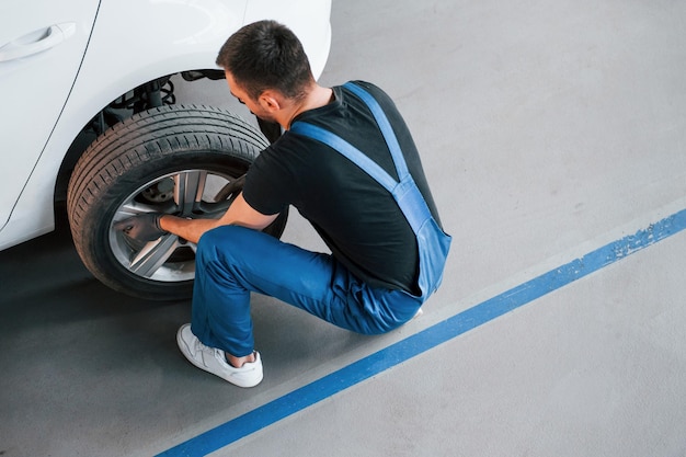 写真 作業服の男が屋内で車のホイールを着替えて着替える自動車サービスの概念