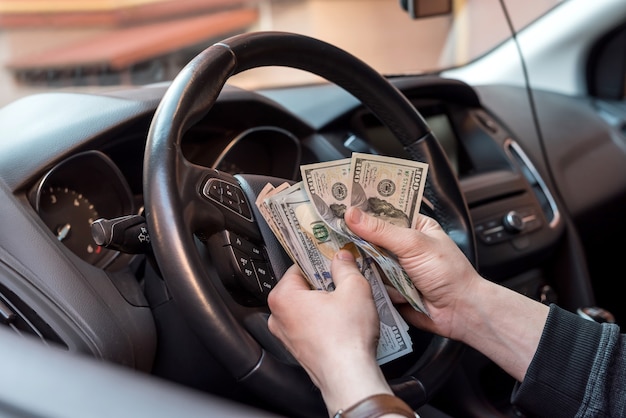 Man in zijn auto telt ons geld, rekeningen voor loon. financieel concept