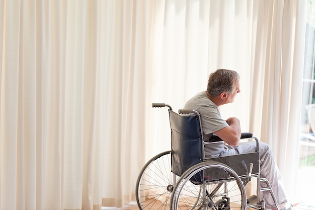 Man in zijn rolstoel kijkt uit het raam