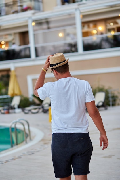 Man in zomerhoed bij het zwembad Zomervakantie concept Hoge kwaliteit foto