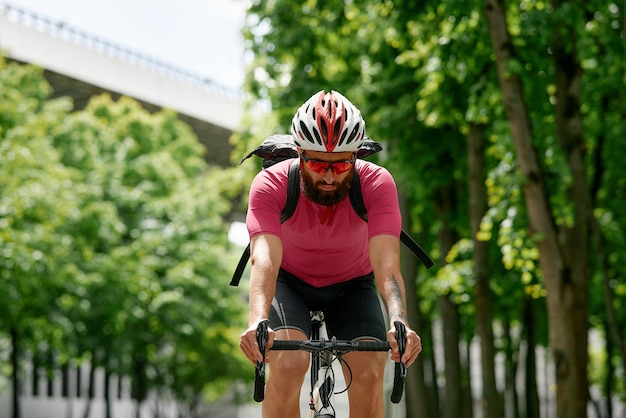 Man in zonnebril snelt langs de weg tegen een achtergrond van zomerpark man met een fietshobby rijdt in het park