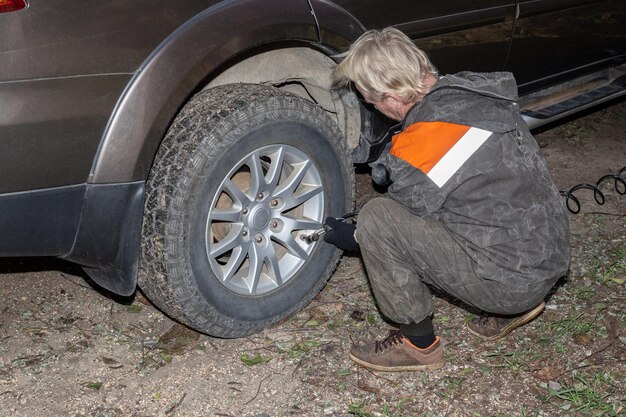 Man inflates a wheel of a car with an electric mobile compressor.