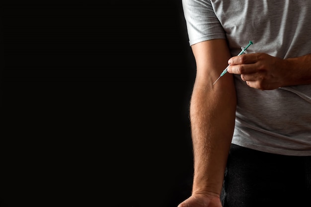 A man injects a syringe into a vein