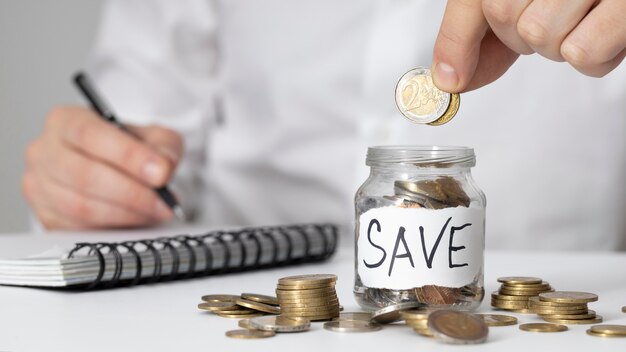 Photo man inserting a coin in savings jar