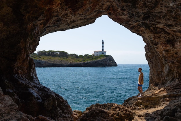 Man inside cave view Lighthouse Portocolom in Mallorca