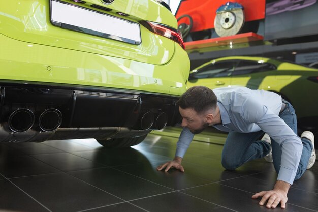 Un uomo che ispeziona un'auto nuova appena acquistata in un concessionario di automobili