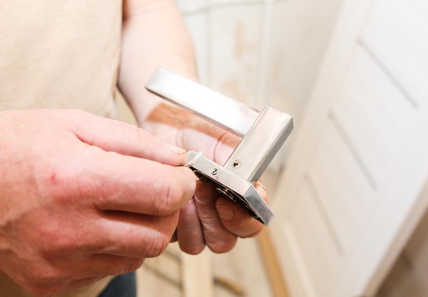 Man installeert de deurklink Reparatiewerkzaamheden Onderhoud in het appartement