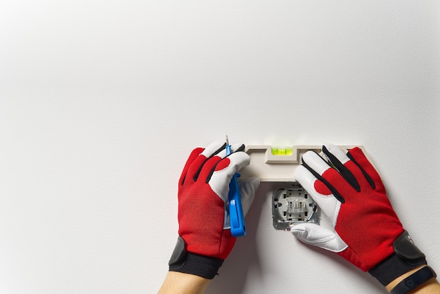 Man installing light switch after home renovation. electrician installing light switch on painted wall with screwdriver