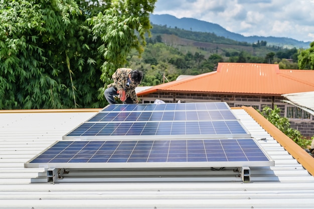 代替エネルギー太陽光発電の安全なエネルギーのために屋根の家にソーラーパネルを設置する男。自然からの電力太陽光発電太陽電池発電機は地球を救う