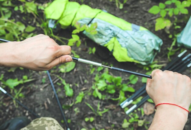 Man installing tent. Tourist outdoors. Camping in the forest.