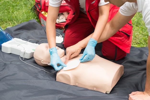 Photo man instructing while paramedic practicing cpr on dummy