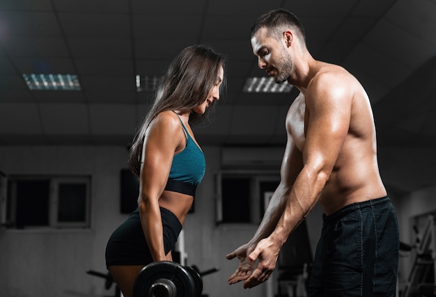 Man instructor and woman train, lifting dumbbells