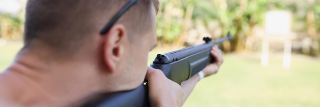 A man is aiming at a target with a gun closeup