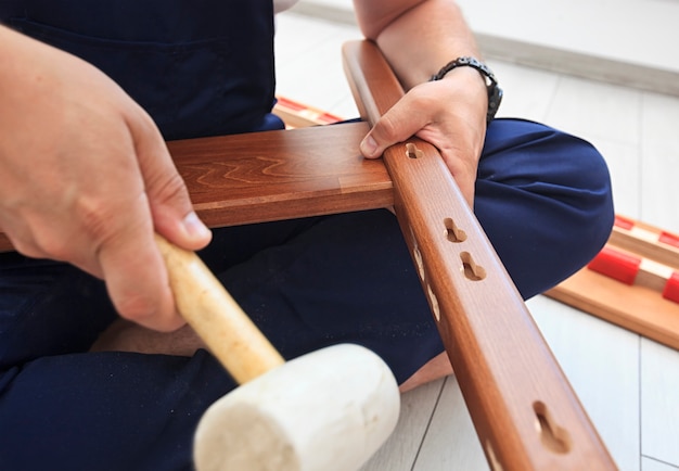 man is assembling wooden furniture in home