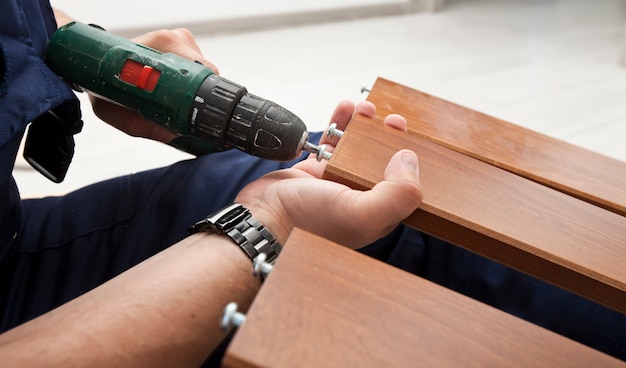 Photo the man is assembling wooden furniture in home