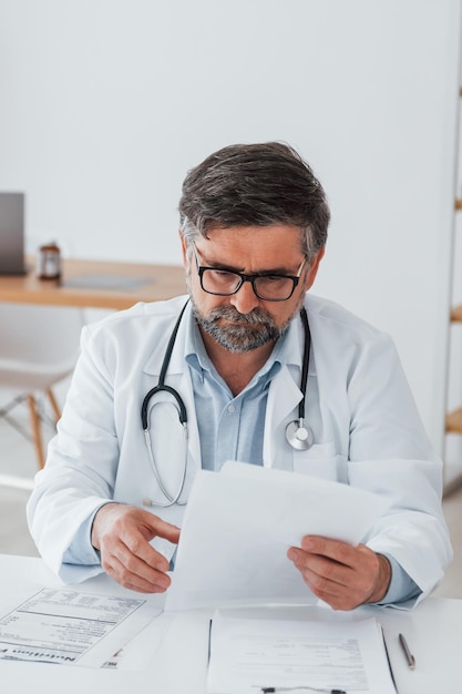 Man is busy with documents professional medical worker in white
coat is in the office