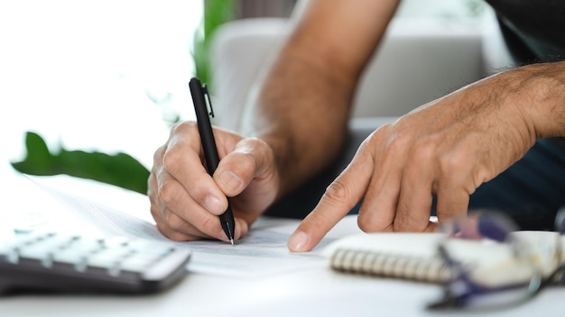 Man is calculating annual tax with calculator and filling form of Individual Income Tax Return