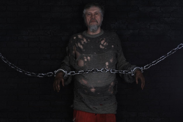 A man is chained to a chain in a dark room.