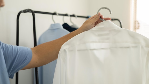 Man is choosing shirt in the clothes room at home