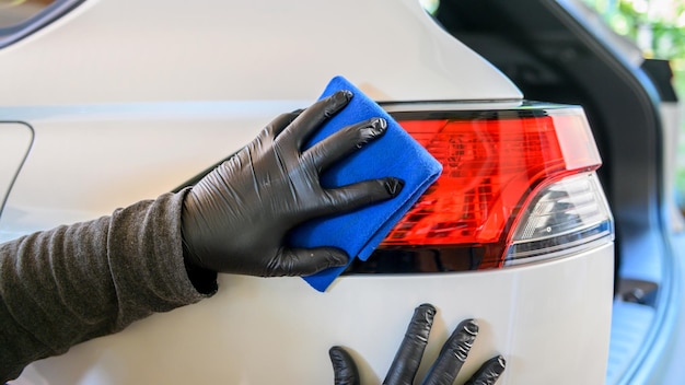 Un uomo sta pulendo l'auto con un panno in microfibra. lavaggio auto in garage a casa.