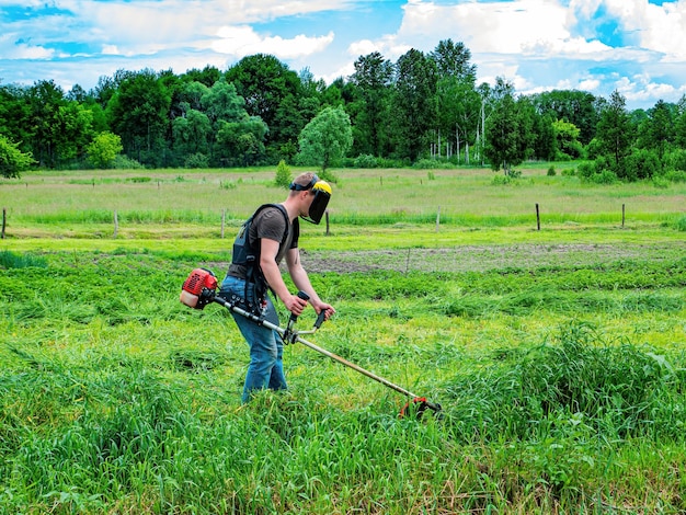 A man is cutting green grass with a lawnmower