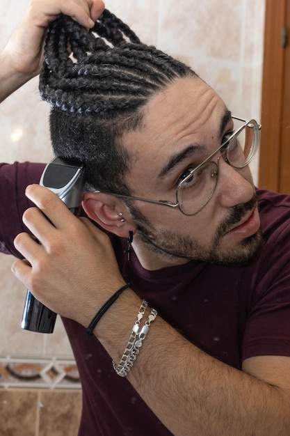 A man is cutting his hair with a hair clipper in the bathroom\
close up of man cutting his hair with hair clipper in the\
bathroom