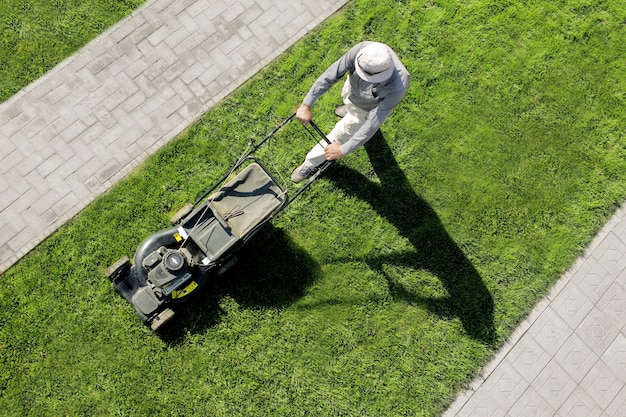 Photo the man is cutting the lawn