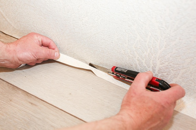 Man is cutting wallpaper. Maintenance repair works renovation in the flat. Restoration indoors.