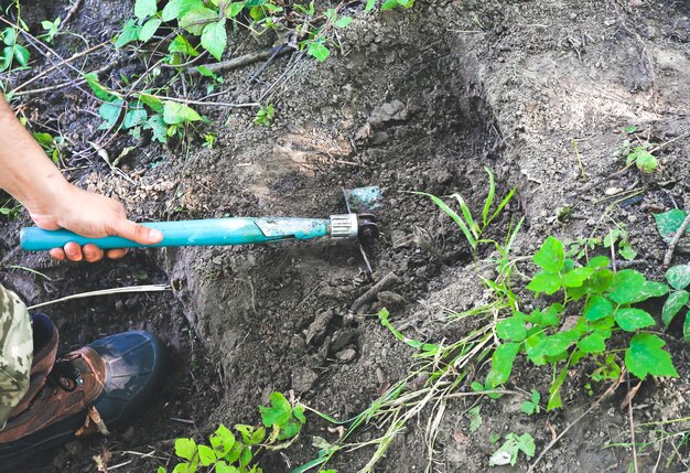 男はシャベルで地面を掘っています。自然の中の観光客。屋外で階段を作る。