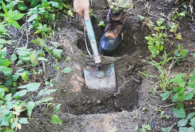 男はシャベルで地面を掘っています。自然の中の観光客。屋外で階段を作る。