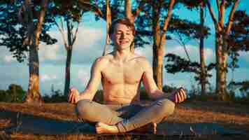 Photo a man is doing yoga in a park with trees in the background