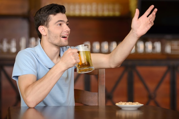 写真 男はバーでビールを飲み、ウェイターにアピールしています。