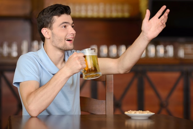 Man is drinking beer at the bar and appeal to the waiter.