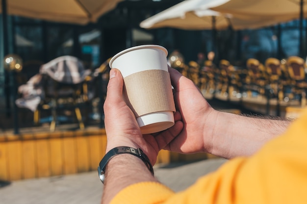 男性が屋外レストランでコーヒーを飲んでいます。