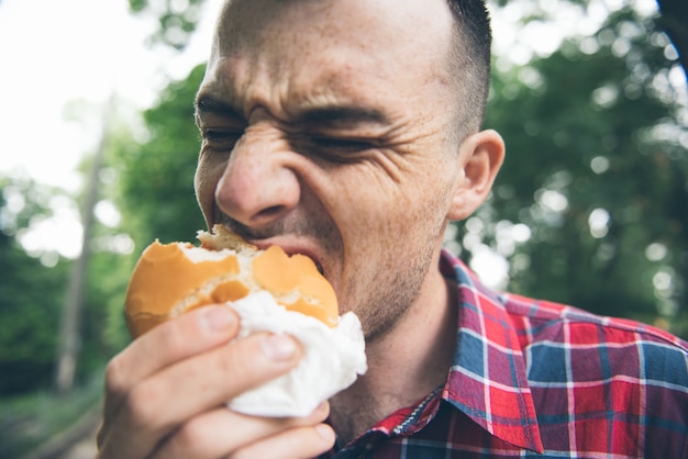 Man is eating in the park and enjoying delicious food