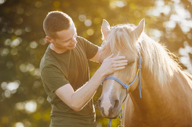 Foto l'uomo sta abbracciando la terapia dei cavalli, l'ippoterapia e l'amicizia tra persone e animali.