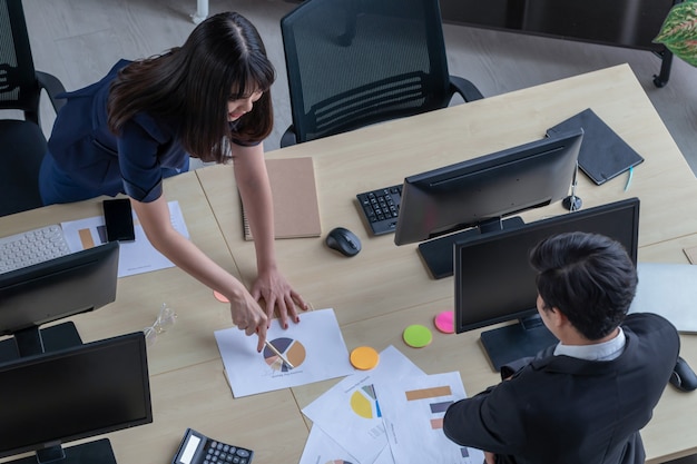 A man is explaining work to a girl at the desk.