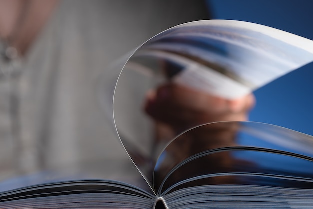 man is flipping through a book. Focus on book binding.