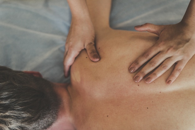 A man is given a back massage. Relaxation on the massage table. Beautiful tinted