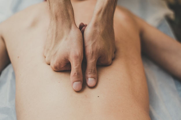 A man is given a back massage. Relaxation on the massage table. Beautiful tinted