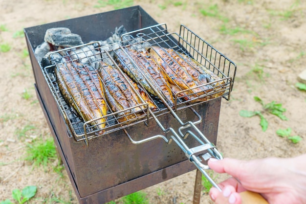 男性がトングでグリルを焼いています。