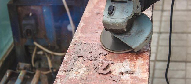 A man is grinding a board Removing old paint from boards Carpentry work