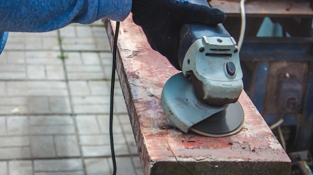 A man is grinding a board Removing old paint from boards Carpentry work